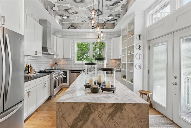 kitchen with appliances with stainless steel finishes, white cabinetry, tasteful backsplash, and light wood-style floors