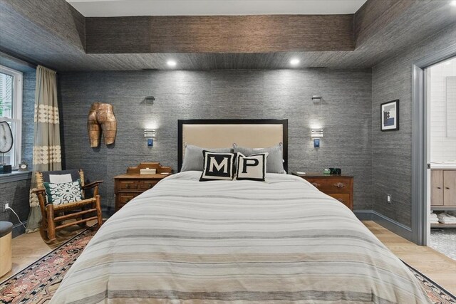 bedroom with wallpapered walls, wood finished floors, and baseboards