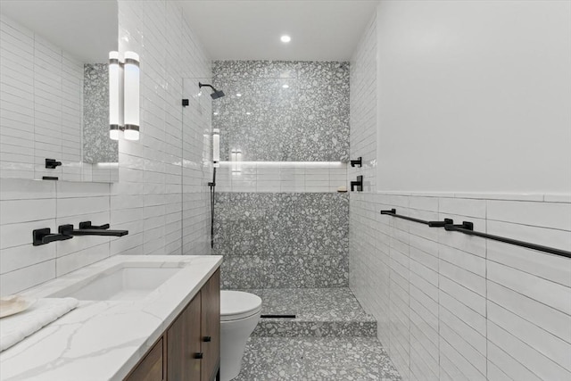 bathroom featuring tile walls, a walk in shower, tile patterned flooring, toilet, and vanity