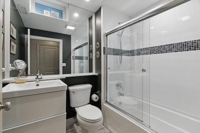 bathroom featuring combined bath / shower with glass door, toilet, and vanity