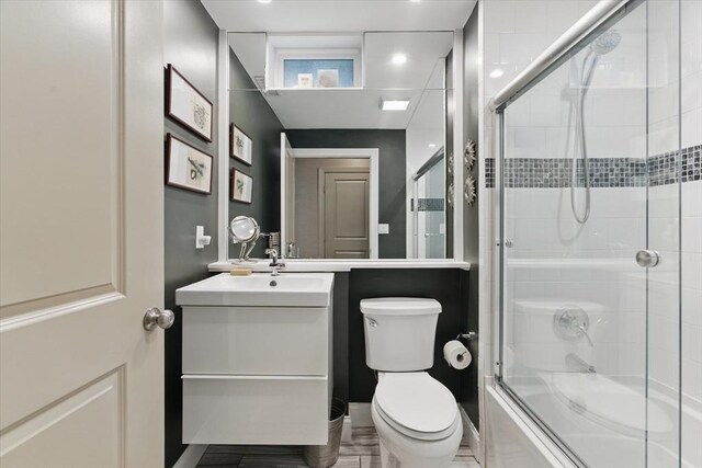 bathroom featuring toilet, vanity, and enclosed tub / shower combo