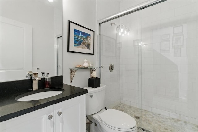 bathroom featuring a shower stall, toilet, and vanity