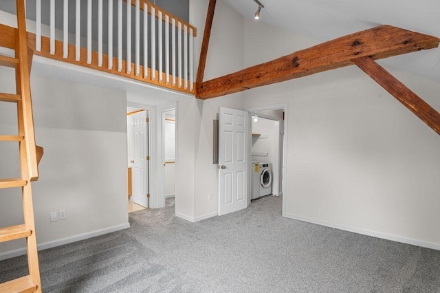 unfurnished living room featuring carpet, baseboards, rail lighting, high vaulted ceiling, and washer and clothes dryer