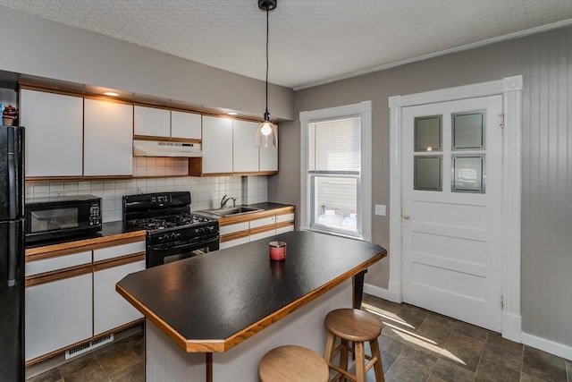 50 Duryea St, Springfield, MA 01104 - kitchen with black appliances, under cabinet range hood, a sink, dark countertops, and white cabinets