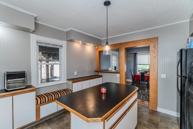 50 Duryea St, Springfield, MA 01104 - kitchen featuring freestanding refrigerator, dark countertops, white cabinets, crown molding, and hanging light fixtures