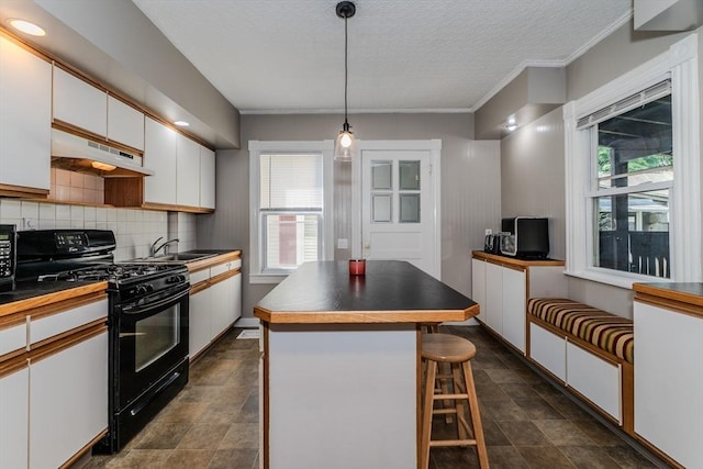 50 Duryea St, Springfield, MA 01104 - kitchen with black gas range oven, under cabinet range hood, white cabinets, decorative backsplash, and plenty of natural light