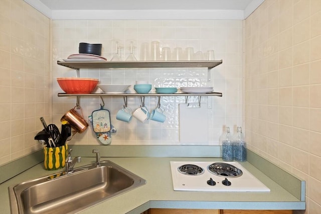 kitchen with open shelves, white electric stovetop, decorative backsplash, and a sink