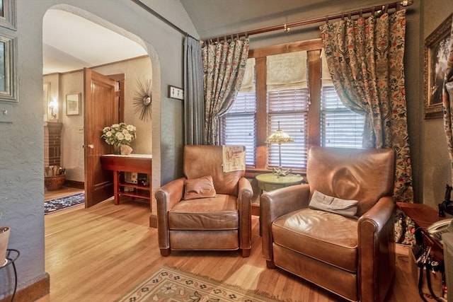 1142 Longmeadow St, Longmeadow, MA 01106 - living area featuring arched walkways, wood finished floors, lofted ceiling, and a textured wall