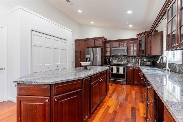 kitchen with light hardwood / wood-style floors, tasteful backsplash, vaulted ceiling, and stainless steel appliances