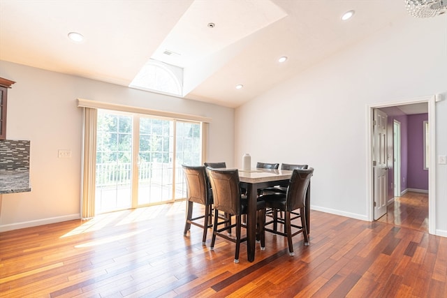 dining area with high vaulted ceiling and hardwood / wood-style floors