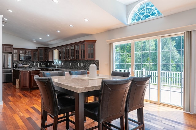 dining room featuring lofted ceiling, light hardwood / wood-style floors, and sink