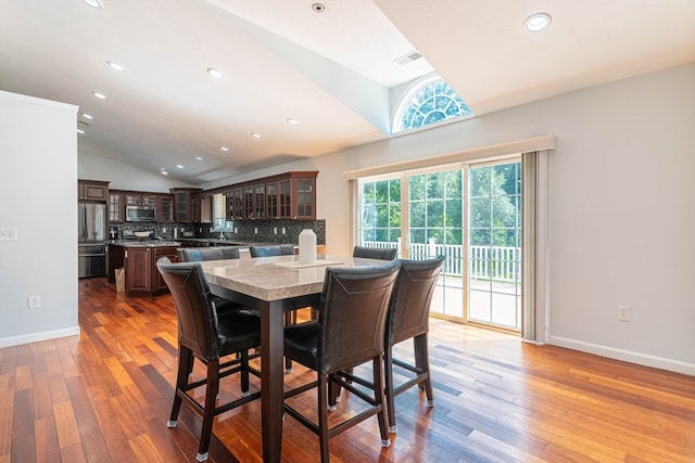 dining area with light hardwood / wood-style floors and vaulted ceiling