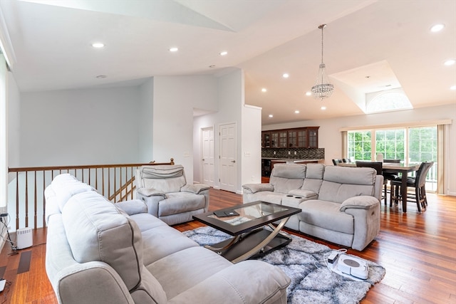 living room with high vaulted ceiling, an inviting chandelier, and hardwood / wood-style floors