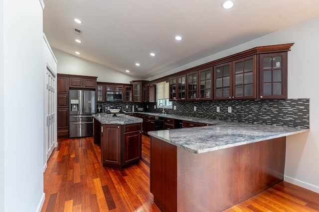 kitchen with appliances with stainless steel finishes, tasteful backsplash, light stone counters, kitchen peninsula, and dark hardwood / wood-style flooring