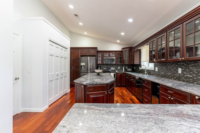 kitchen featuring light stone counters, dark hardwood / wood-style floors, a kitchen island, appliances with stainless steel finishes, and backsplash