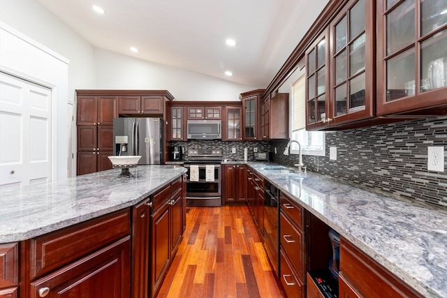 kitchen with lofted ceiling, light hardwood / wood-style flooring, backsplash, stainless steel appliances, and sink