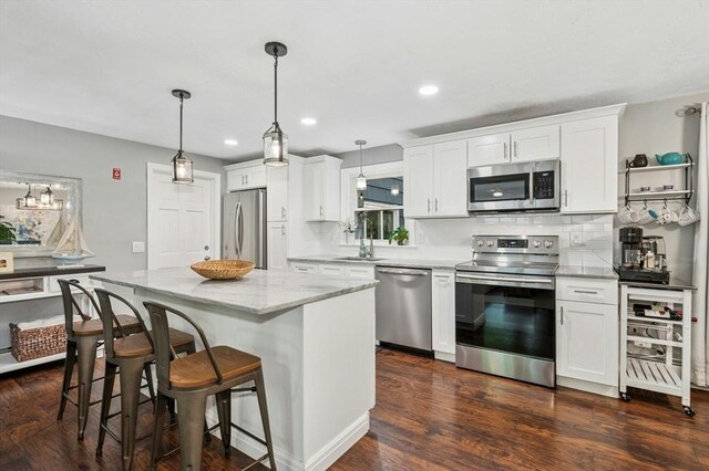 41 Dick Dr, Worcester, MA 01609 - kitchen with stainless steel appliances, a breakfast bar area, a kitchen island, backsplash, and white cabinetry