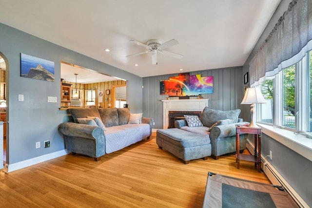 329 Brooklawn Ave, New Bedford, MA 02745 - living room with baseboard heating, a ceiling fan, light wood finished floors, baseboards, and a brick fireplace