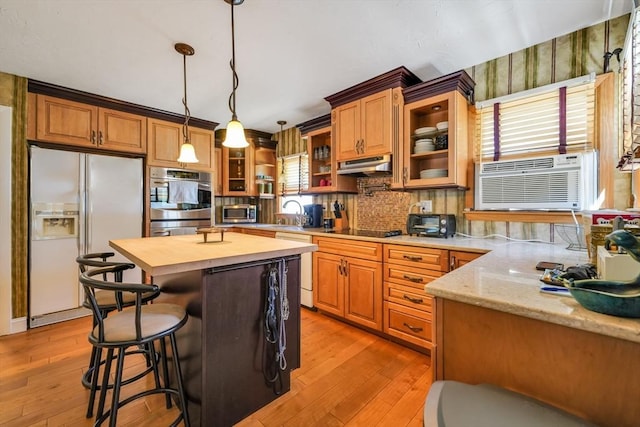 329 Brooklawn Ave, New Bedford, MA 02745 - kitchen featuring appliances with stainless steel finishes, under cabinet range hood, light wood-style flooring, and a kitchen bar