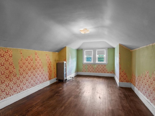 bonus room with radiator heating unit, hardwood / wood-style floors, lofted ceiling, wallpapered walls, and baseboards