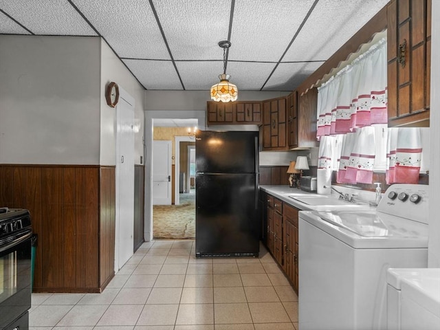 kitchen featuring black appliances, a sink, a drop ceiling, light countertops, and wainscoting