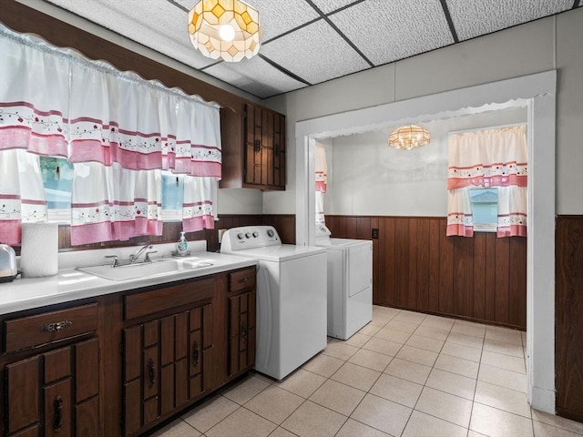 clothes washing area with a wainscoted wall, cabinet space, wood walls, light tile patterned flooring, and washing machine and dryer