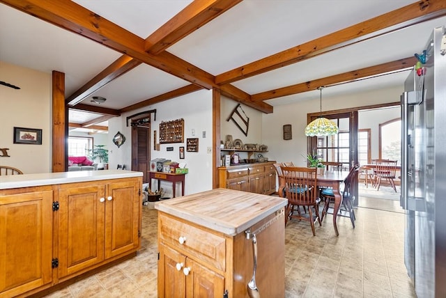 kitchen featuring butcher block countertops, a center island, a healthy amount of sunlight, decorative light fixtures, and beamed ceiling