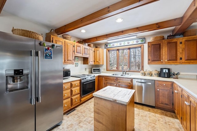 kitchen with a center island, appliances with stainless steel finishes, sink, and beam ceiling