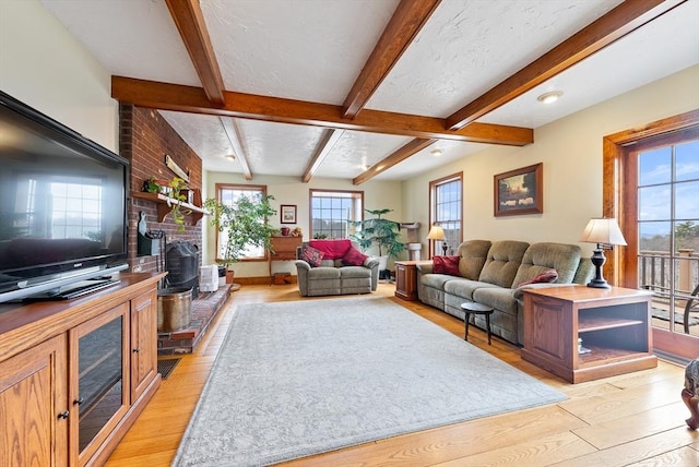 living room featuring beam ceiling, light hardwood / wood-style flooring, and a wood stove