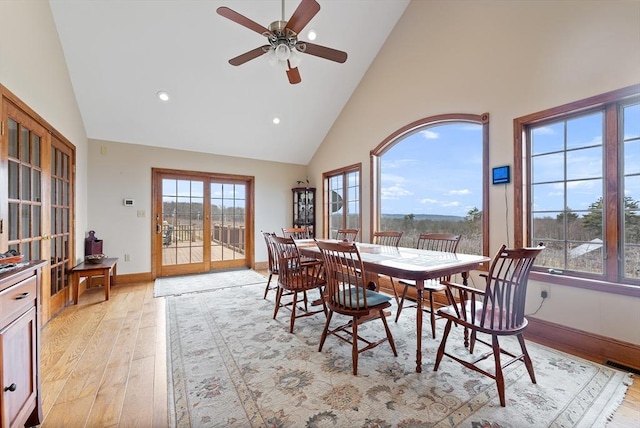 dining room featuring ceiling fan, plenty of natural light, high vaulted ceiling, and light wood-type flooring