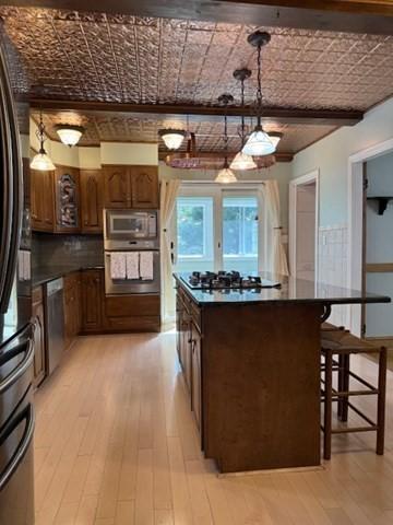 17 Olcott St, Watertown, MA 02472 - kitchen featuring light wood-style floors, a kitchen island, dark countertops, and stainless steel appliances