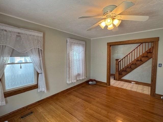 17 Olcott St, Watertown, MA 02472 - unfurnished living room with ceiling fan, a textured ceiling, stairs, wood finished floors, and visible vents