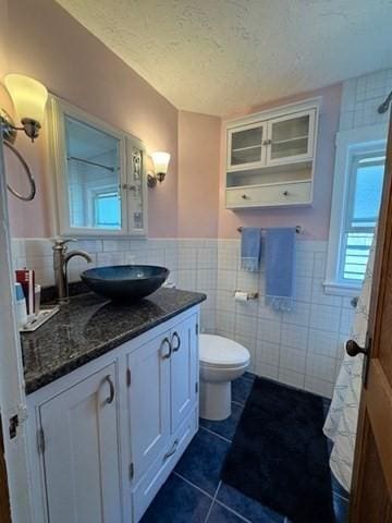 17 Olcott St, Watertown, MA 02472 - full bathroom with vanity, wainscoting, toilet, tile walls, and tile patterned floors