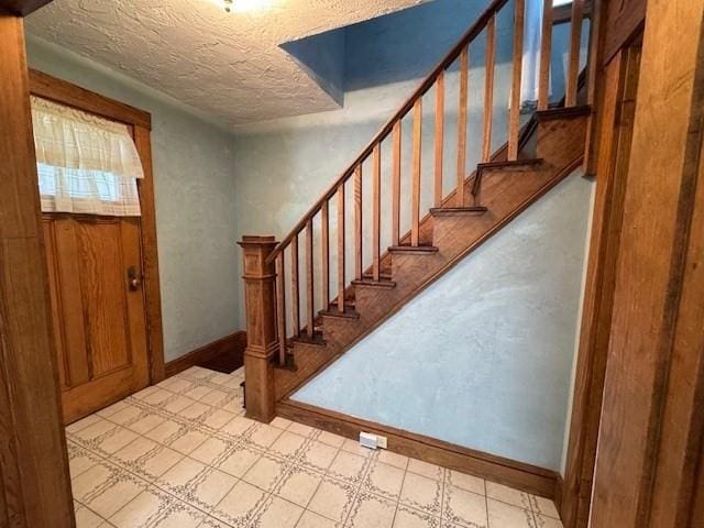 17 Olcott St, Watertown, MA 02472 - entrance foyer featuring baseboards, a textured ceiling, light floors, and stairway