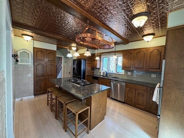17 Olcott St, Watertown, MA 02472 - kitchen with stainless steel dishwasher, freestanding refrigerator, an ornate ceiling, a kitchen bar, and gas stovetop