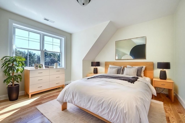 bedroom featuring visible vents, light wood finished floors, and baseboards