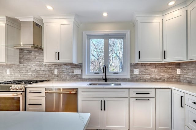 kitchen with wall chimney exhaust hood, stainless steel appliances, a sink, tasteful backsplash, and white cabinetry