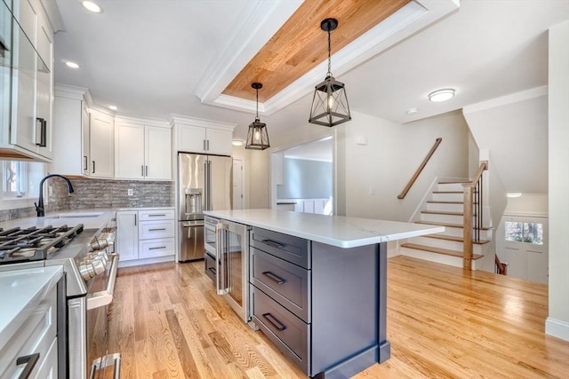 kitchen featuring stainless steel appliances, a sink, light wood-type flooring, a kitchen island, and white cabinetry