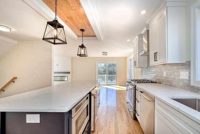 kitchen featuring white cabinets, light wood finished floors, a center island, tasteful backsplash, and appliances with stainless steel finishes