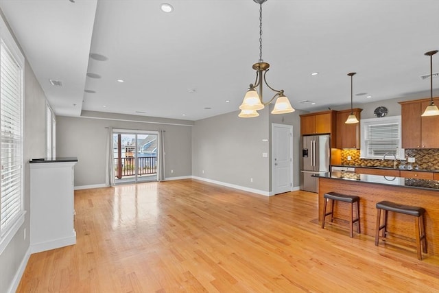 kitchen with hanging light fixtures, a breakfast bar, decorative backsplash, high end refrigerator, and sink