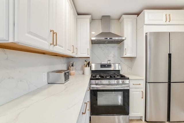 kitchen featuring appliances with stainless steel finishes, white cabinets, light stone counters, and wall chimney range hood