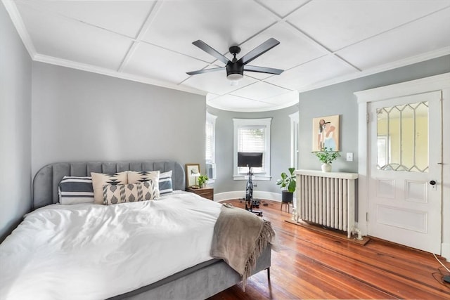 bedroom with hardwood / wood-style floors, radiator, ornamental molding, ceiling fan, and coffered ceiling