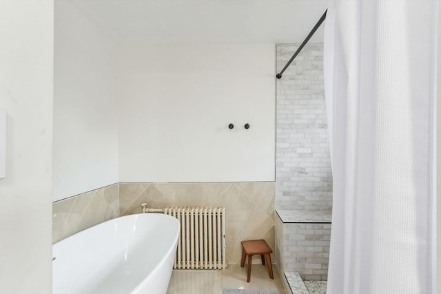 bathroom with separate shower and tub, radiator, and tile walls