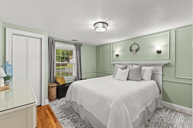45 S Elm St, West Bridgewater, MA 02379 - bedroom featuring a textured ceiling, a decorative wall, light wood-type flooring, and a closet