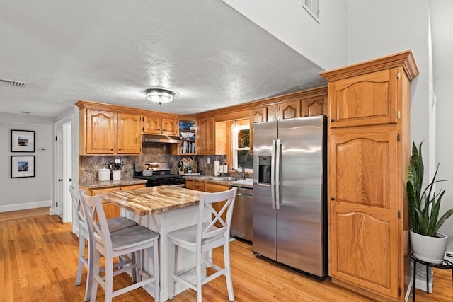45 S Elm St, West Bridgewater, MA 02379 - kitchen with stainless steel appliances, under cabinet range hood, wood counters, a kitchen breakfast bar, and light wood-type flooring
