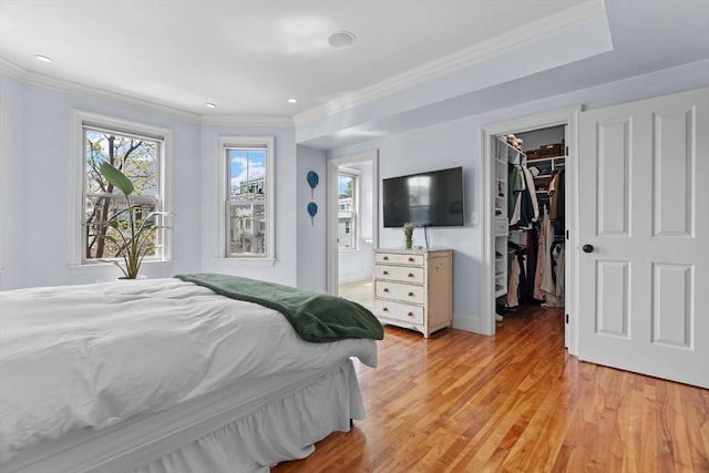 bedroom with a closet, recessed lighting, light wood finished floors, crown molding, and a spacious closet