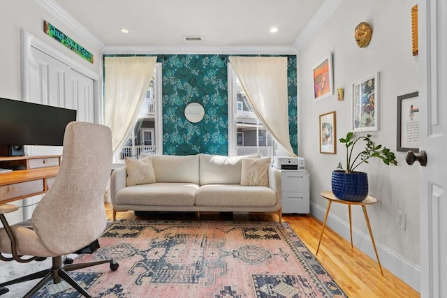 sitting room with wallpapered walls, baseboards, visible vents, crown molding, and wood finished floors