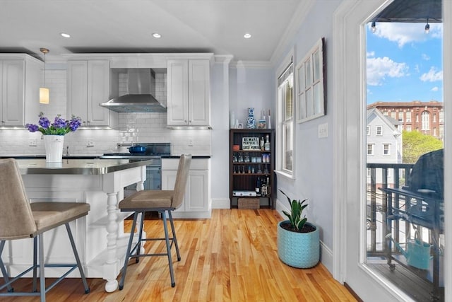 kitchen featuring light wood finished floors, wall chimney exhaust hood, electric stove, decorative backsplash, and ornamental molding