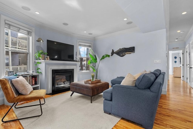 living area featuring a fireplace with flush hearth, ornamental molding, light wood-type flooring, and recessed lighting