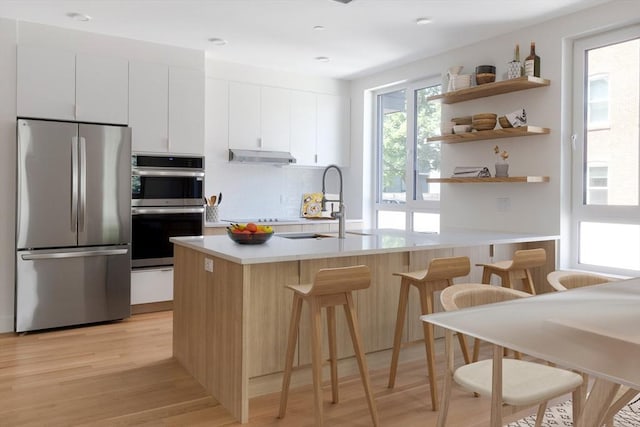 213 Harvard Unit 4, Cambridge, MA 02139 - kitchen featuring stainless steel appliances, light wood-style flooring, light countertops, and white cabinetry
